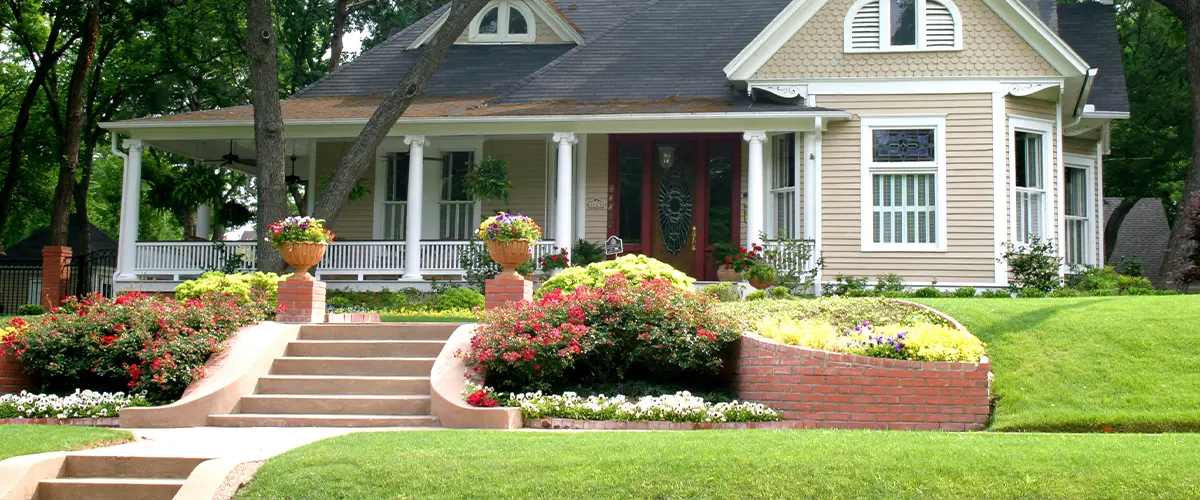 Charming house with well-manicured garden, red brick steps, and lush greenery.