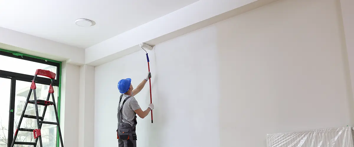 Painter in blue cap applying Ceiling Painting in White Bluff, TN, ladder and paint supplies nearby.