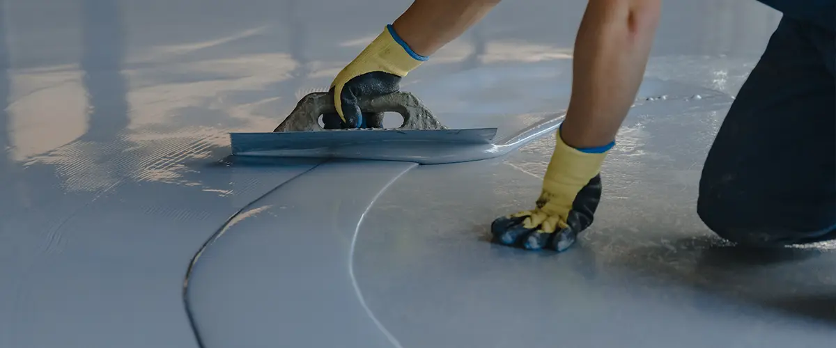 The worker applies gray epoxy resin to the new floor