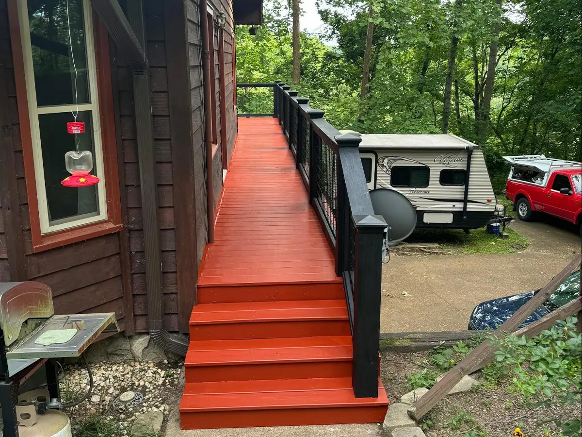 a house with a red and black porch and stairs, freshly painted
