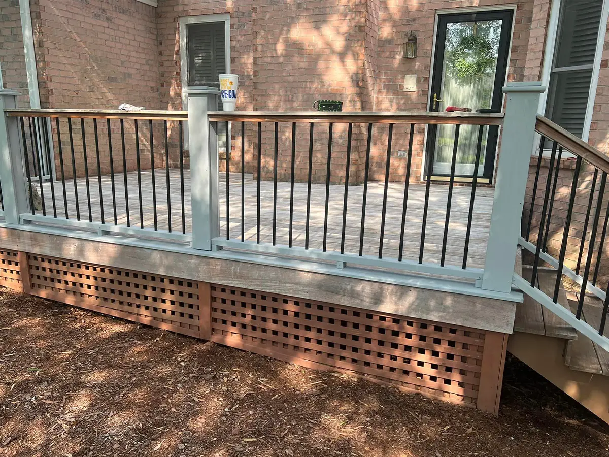 a deck with a railing and a brick building