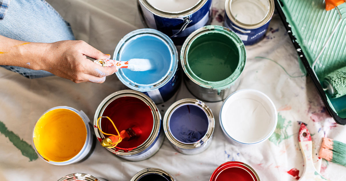 Open paint cans with various colors and a roller tray, ideal for home painting and DIY interior wall renovation projects.