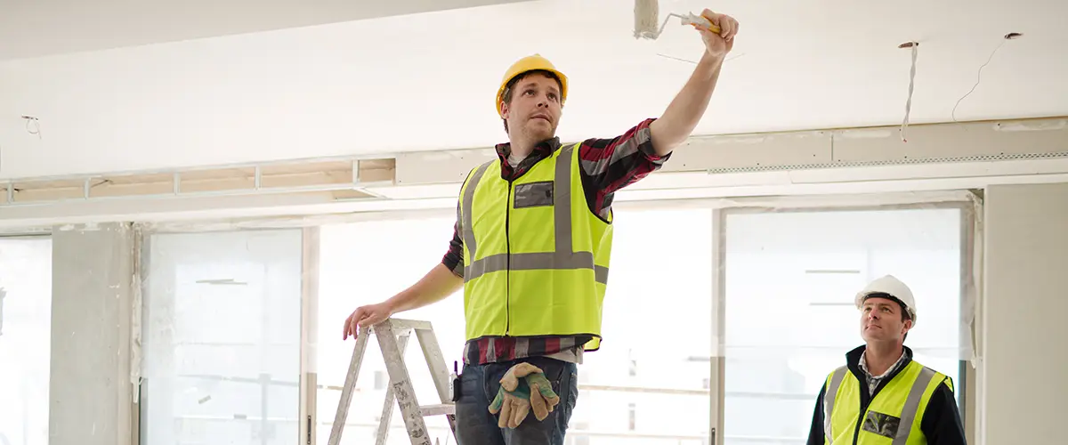 a team of painters painting the ceiling of a commercial space