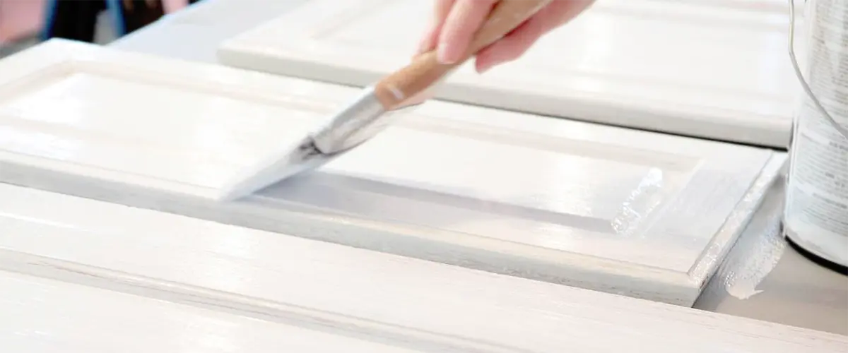 Close-up of hand painting cabinet door white with a brus