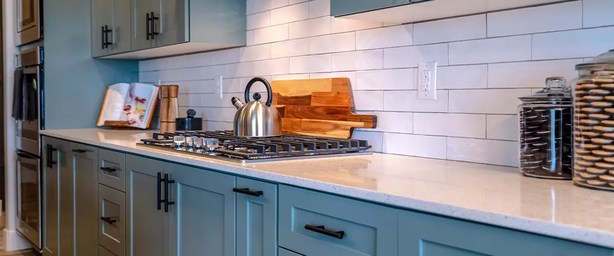 Painted kitchen cabinets with white tile backsplash and stainless steel stove