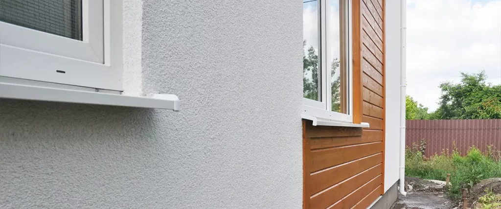 Close-up of textured exterior wall with white windows and wood siding