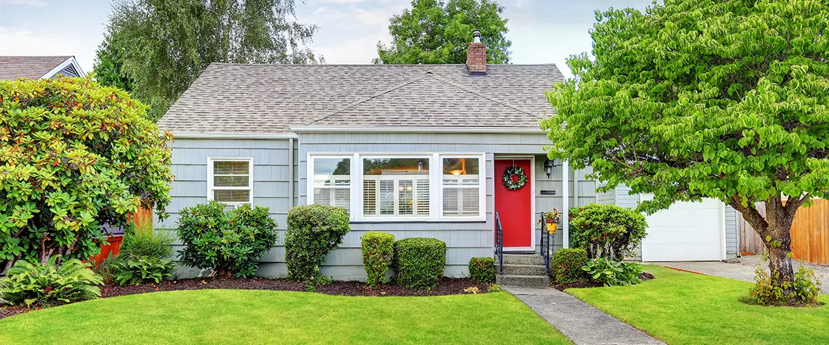 Brightly painted house with red door and well-kept landscaping