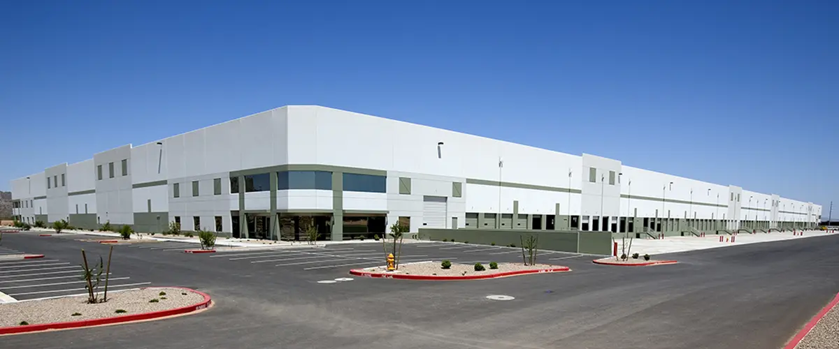 Large white warehouse with clean painted exterior and empty parking lot