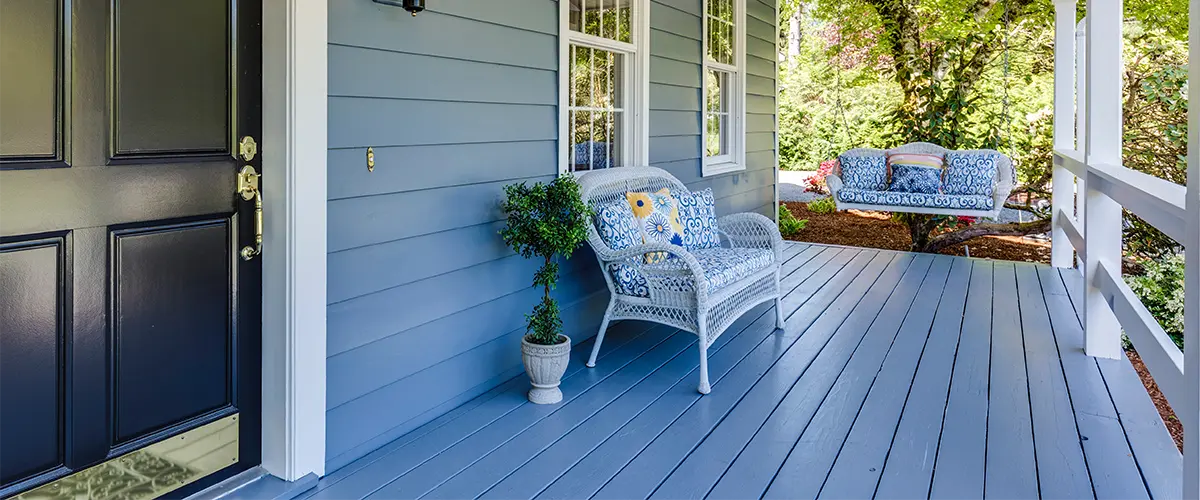 Painted front porch with blue siding and white outdoor furniture