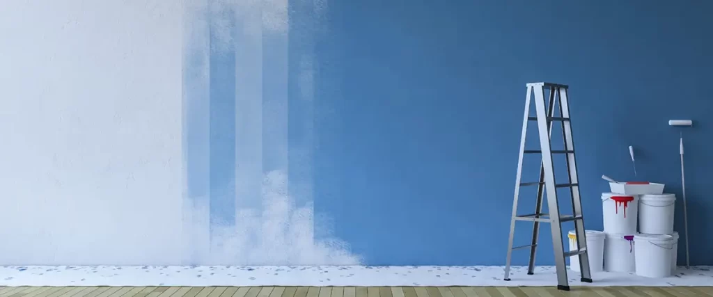 Blue accent wall being painted with roller and ladder nearby