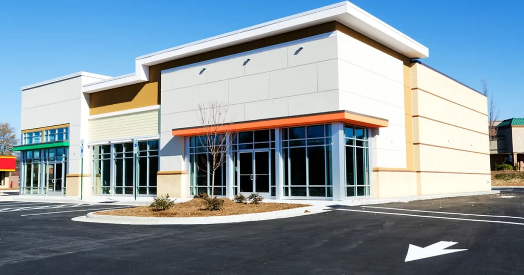 commercial painting modern commercial building with large glass windows beige facade asphalt parking