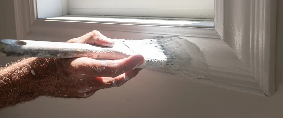 Hand painting window trim with white paint for a smooth finish