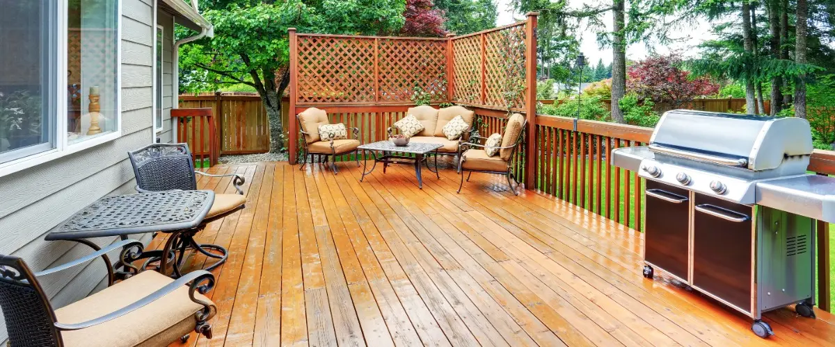 A deck featuring a grill, chairs, and a table, perfect for outdoor dining and relaxation