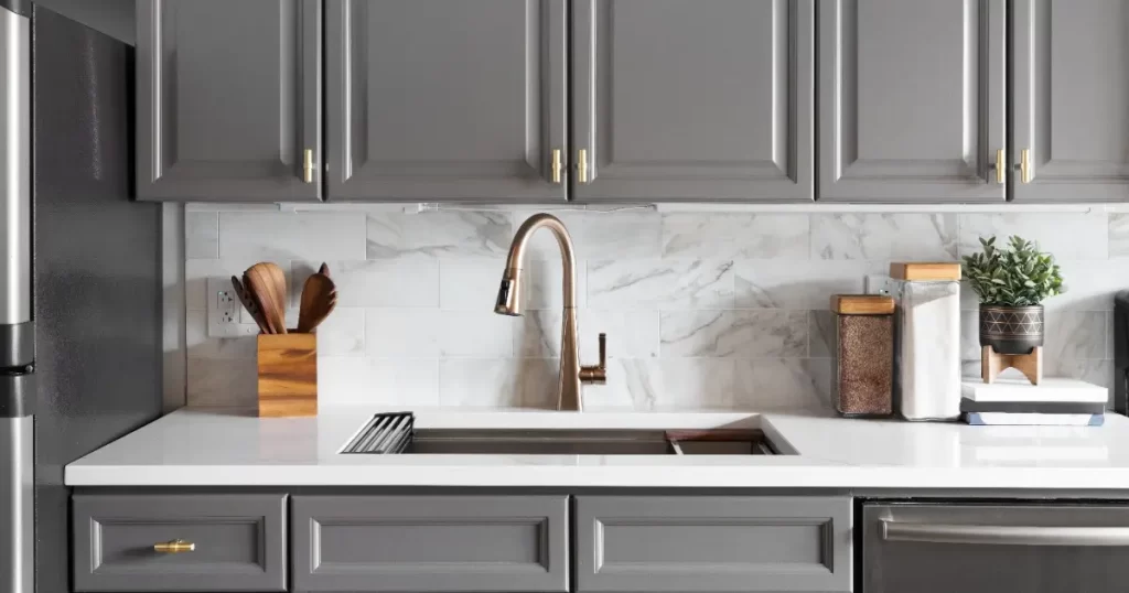 A modern kitchen featuring gray cabinets and a stainless steel sink