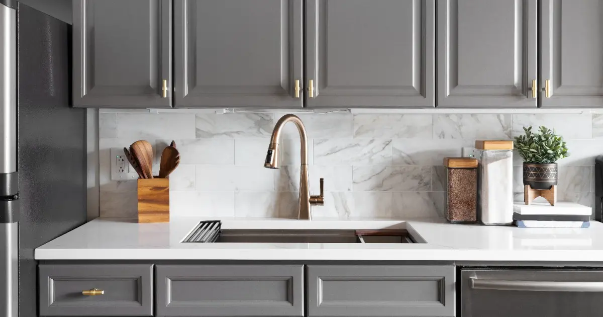 A modern kitchen featuring gray cabinets and a stainless steel sink