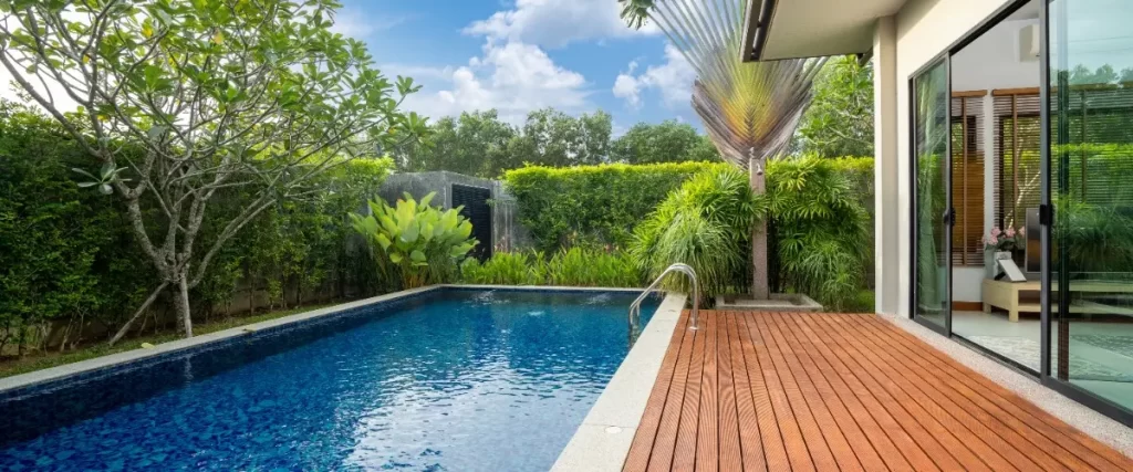 A small pool surrounded by wooden flooring in a backyard setting, creating a relaxing outdoor space