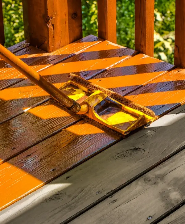 A wooden deck featuring a broom and a paintbrush resting on its surface