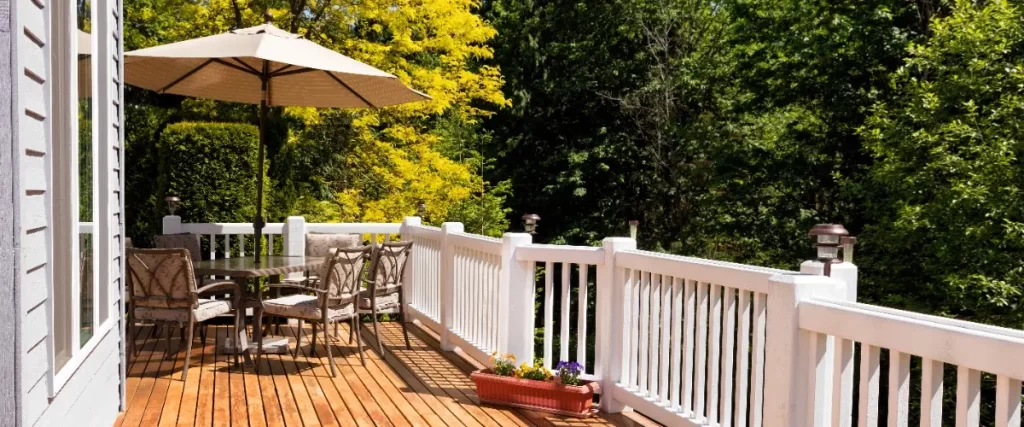 A wooden deck featuring a table surrounded by four chairs, set for outdoor dining