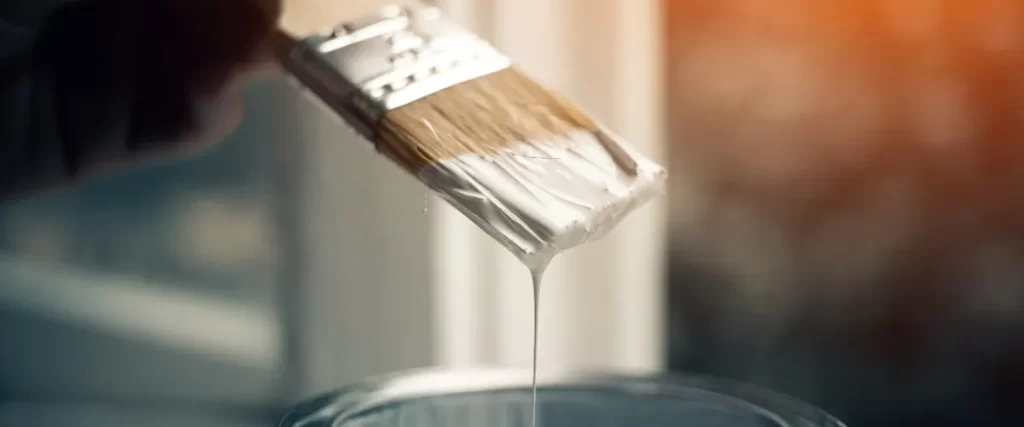a paintbrush being dipped into a container of paint
