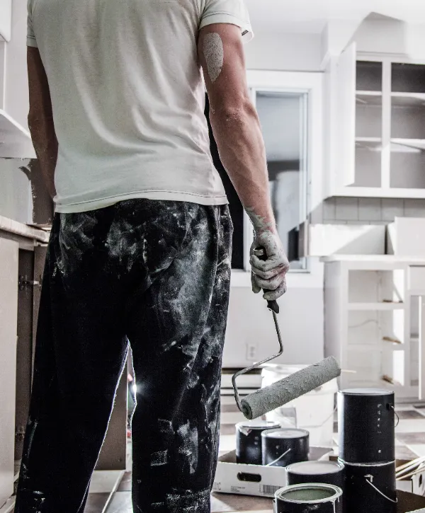a person in a kitchen in the middle of a cabinet painting project.