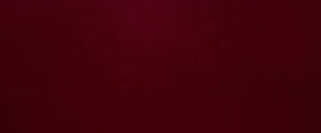 a solid, dark red or burgundy wall with a slightly textured appearance