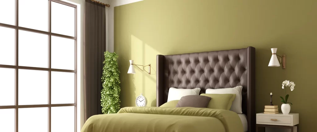 A cozy bedroom featuring a dark brown tufted leather headboard against a smooth olive green painted accent wall.