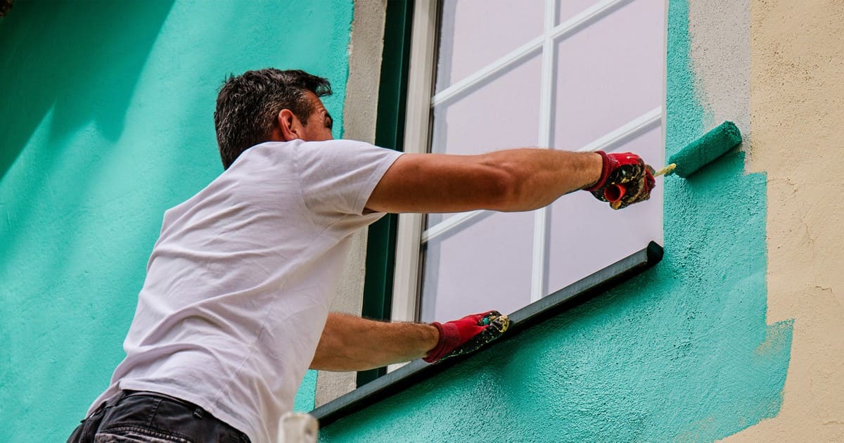 Professional house painters applying teal exterior paint to window trim for a home in Pegram, TN.