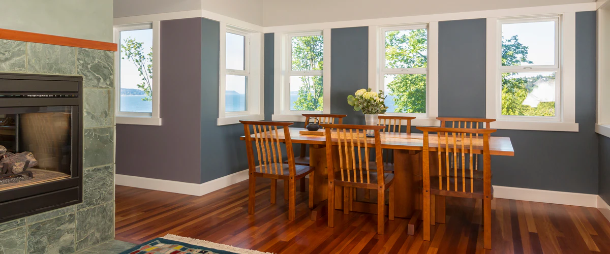 A spacious dining room featuring freshly painted navy blue accent walls and a stone fireplace.