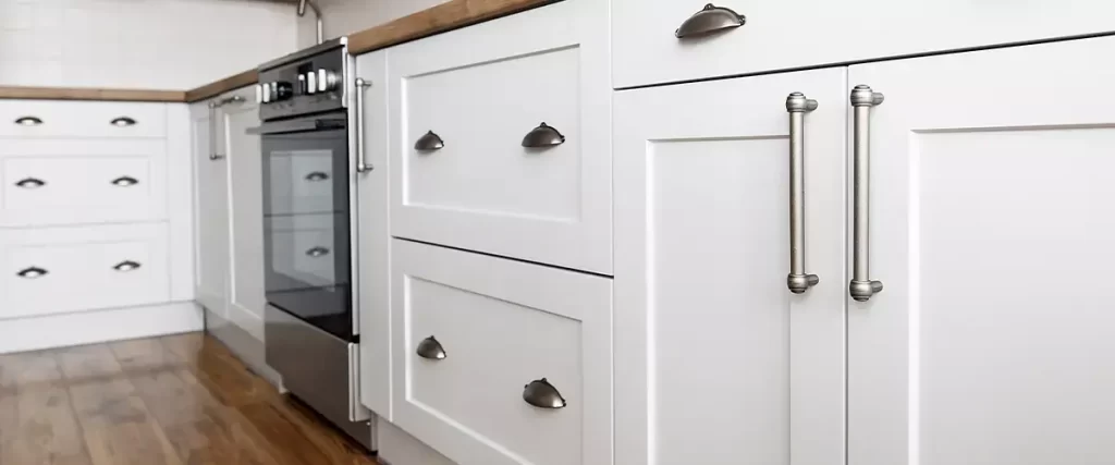 Custom white shaker kitchen cabinets with brushed nickel hardware and wood flooring