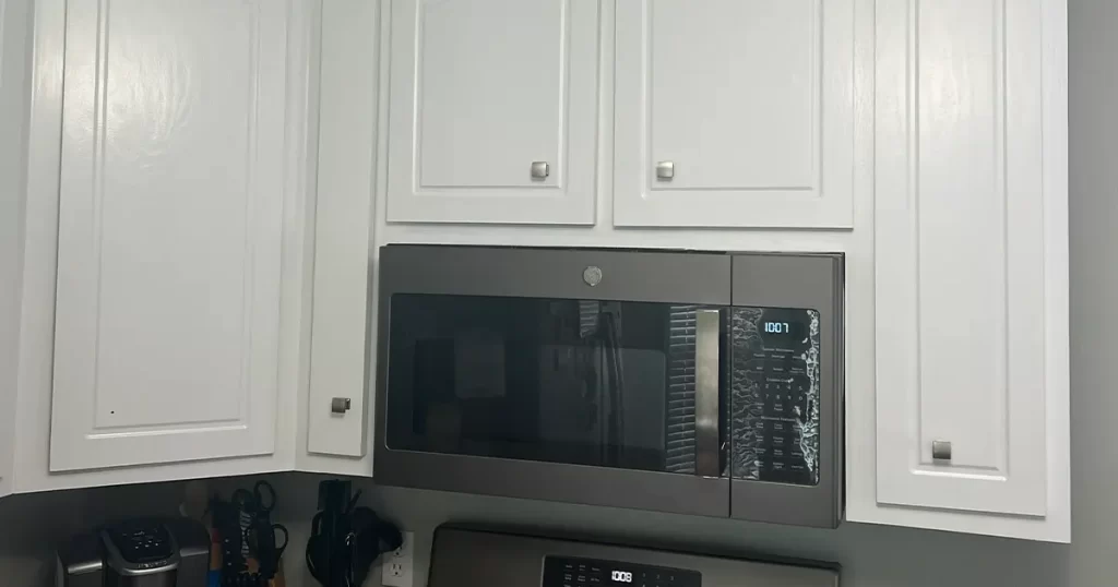 White kitchen cabinets with built-in microwave and modern gray wall paint design